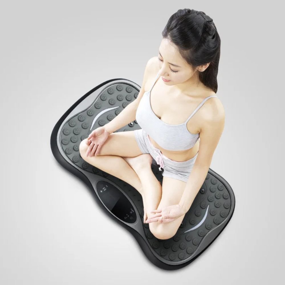 woman meditating while seated on a vibration massage board for home fitness
